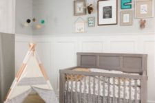 a neutral boho nursery done in greys and pastels, with a printed rug, a grey crib and a teepee