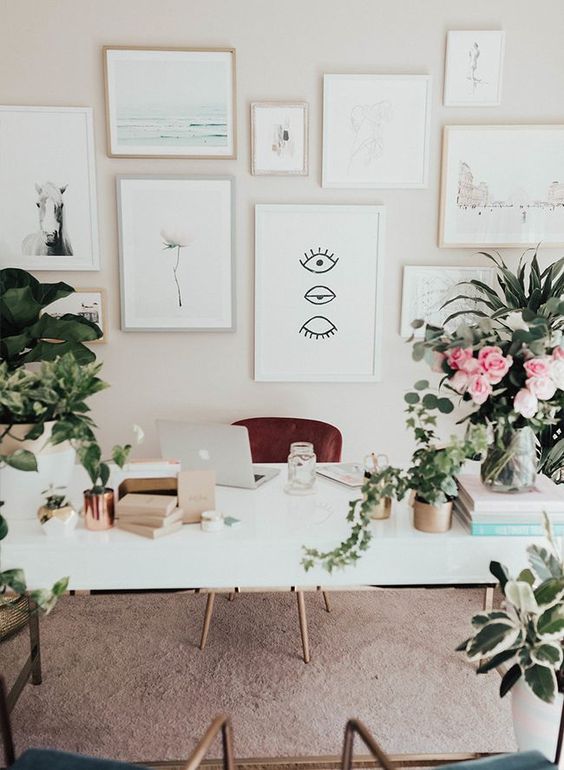 a simple and neutral home office with a neutral gallery wall, potted blooms and greenery and a large white desk
