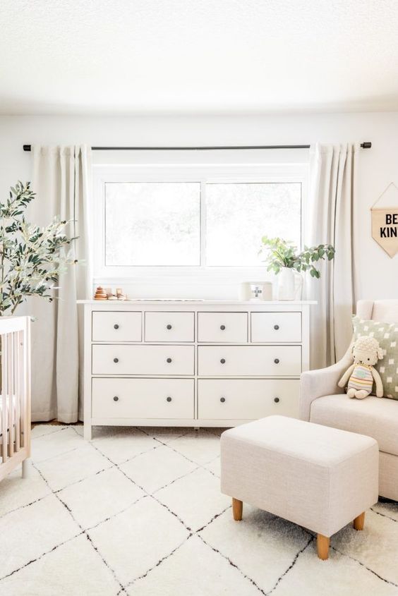 a simple neutral nursery with contemporary neutral furniture, a wooden crib, potted greenery and some toys