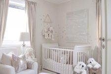 a small neutral nursery with a crib, a white chair and ottoman, baskets with polar bears and a fluffy pendant lamp