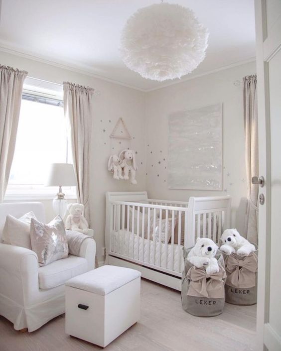 a small neutral nursery with a crib, a white chair and ottoman, baskets with polar bears and a fluffy pendant lamp