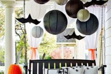 a suspended blakc bench with spider pillows, painted pumpkins, large papper lanterns and paper bats