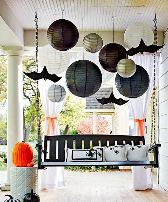 a suspended blakc bench with spider pillows, painted pumpkins, large papper lanterns and paper bats
