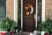 a whimsy Halloween porch with a creative wreath, natural and vine pumpkins, skulls, blooms and greenery