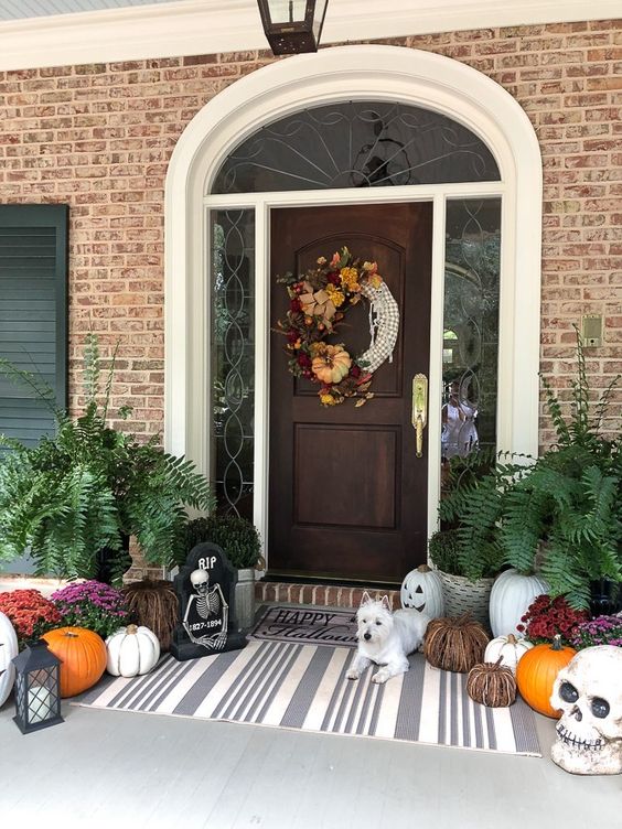 a whimsy Halloween porch with a creative wreath, natural and vine pumpkins, skulls, blooms and greenery