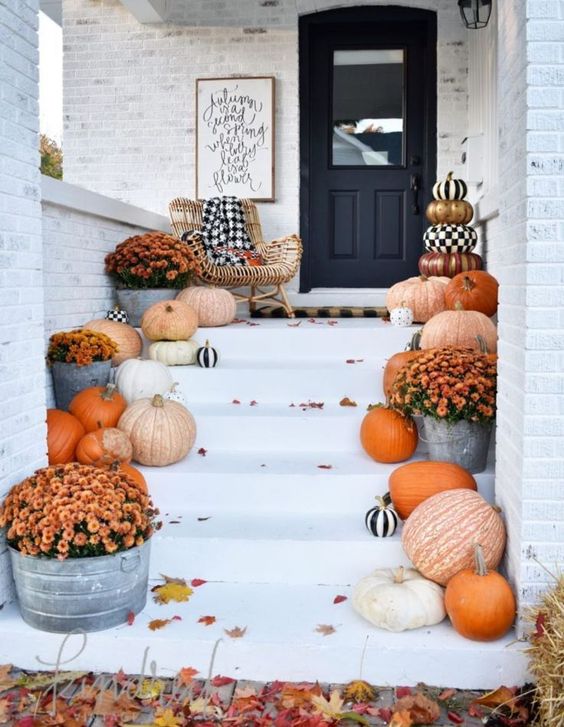 elegant farmhouse porch decor with natural pumpkins, bold fall blooms and touches of black and white for a Halloween feel