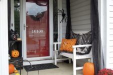 large orange pumpkins, bright fall blooms, spiders and black tulle for simple and fast Halloween porch decor