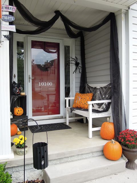 large orange pumpkins, bright fall blooms, spiders and black tulle for simple and fast Halloween porch decor