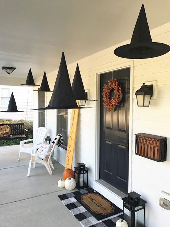 witch hats suspended, natural pumpkins, candle lanterns and a bold fall bloom wreath for a Halloween porch