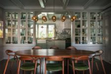 02 The kitchen and dining space are divided with large storage units and the green chairs add color