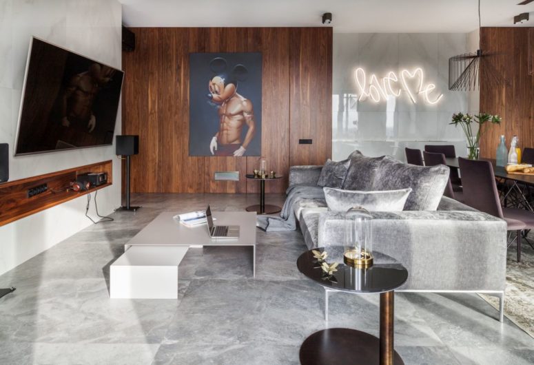 The living area is done with marble tiles, neutral furniture, a whimsy art and a large TV