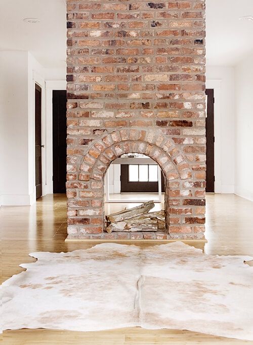 a gorgeous double-sided fireplace clad with brick looks very vintage and brings a character and a story to the room