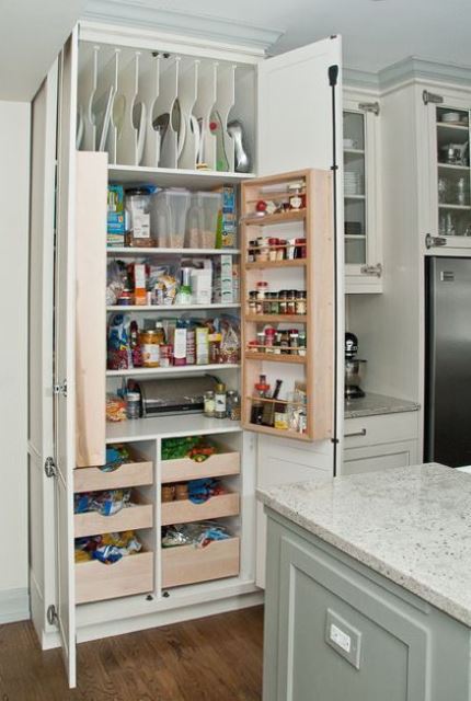 A neutral kitchen with a built in pantry with lots of various shelves and drawers to store everything you may need