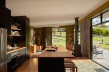 03 The kitchen and living room are united into one space, with a hearth, a large kitchen island with an eating space and dark kitchen furniture