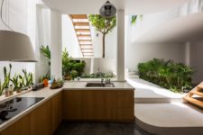 03 The kitchen is done with sleek cabinets, white stone countertops and greenery all along