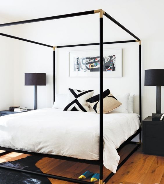 a black canopy bed with gilded corners looks very elegant and chic setting the tone in the bedroom
