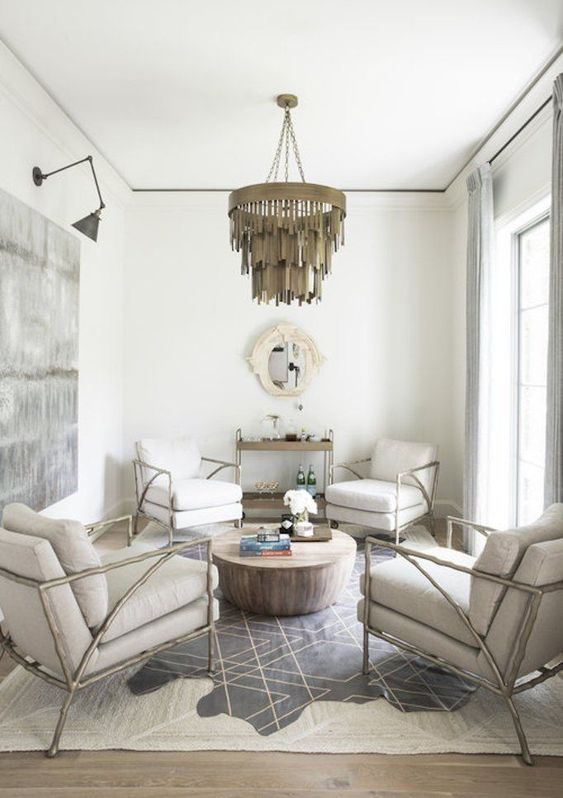 a small sitting space done in neutrals and spruced up with a printed rug, artwork and a bold chandelier