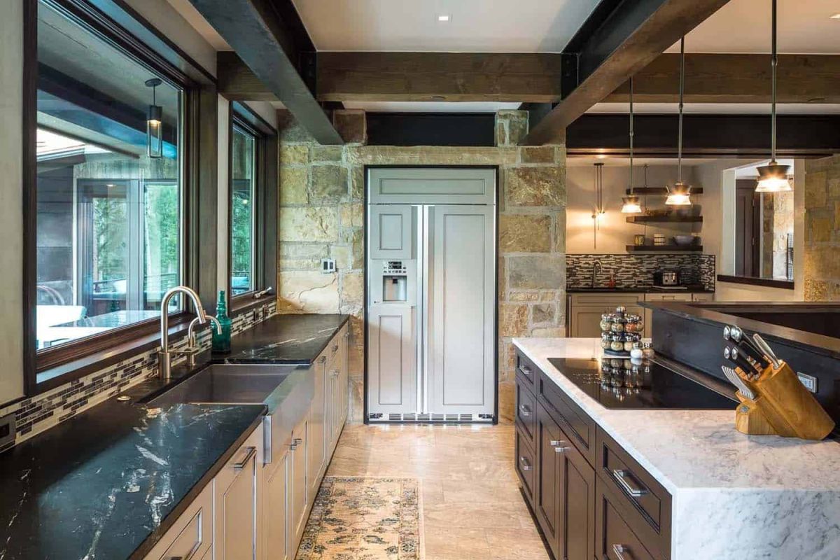 The kitchen is done with white cabinets and black stone countertops, there are stone walls