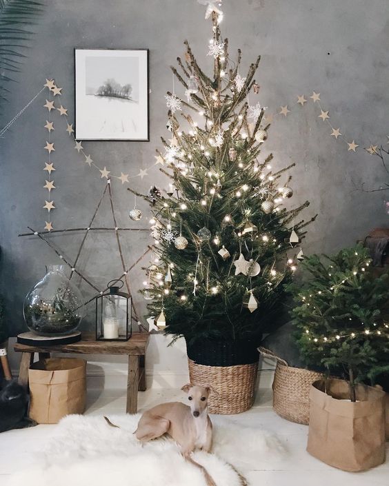 a Christmas tree with lights, white ornaments, baskets, a star garland and a star of twigs