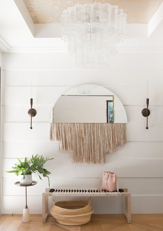 a half circle mirror with long blush fringe is a cool idea for a boho entryway like this one