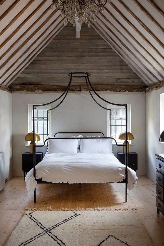 a quirky canopy bed in black on tall legs is a great idea for an eclectic room like this one