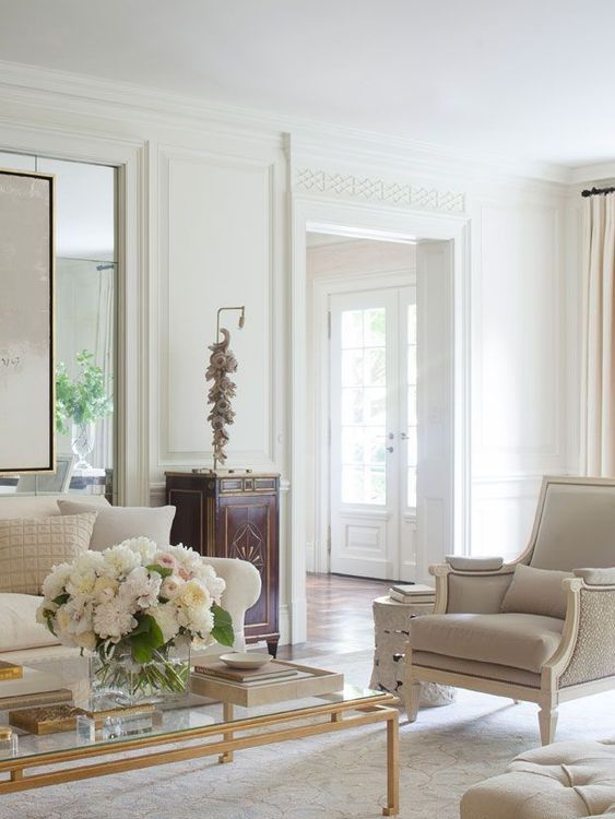 a super elegant neutral living room with chic furniture, an elegant table and a dark cabinet for a colorful touch
