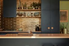 05 The kitchen features a shiny metallic backsplash and wooden handles to create a contrast with dark furniture