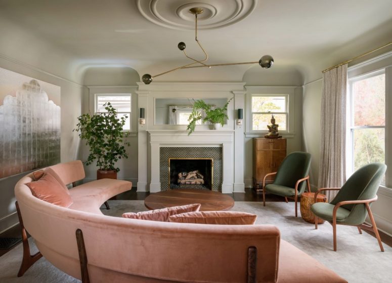 The living room is done with pink and green furniture, a built-in fireplace and greenery in pots