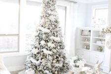 05 a flocked Christmas tree with metallic and white ornaments and lots of gift boxes in white around