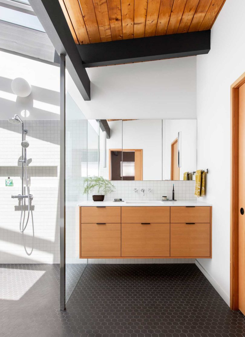 The bathroom features white tiles and black hex ones on the floor, there's a floating vanity