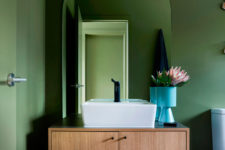 07 The bathroom is also done with green walls, a floating vanity and a square sink plus dark fixtures