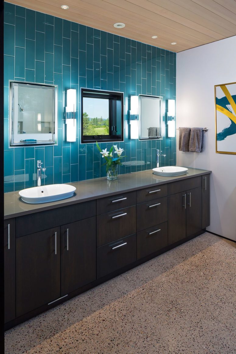 The bathroom is done with dark furniture and blue tiles to connect it to the kitchen