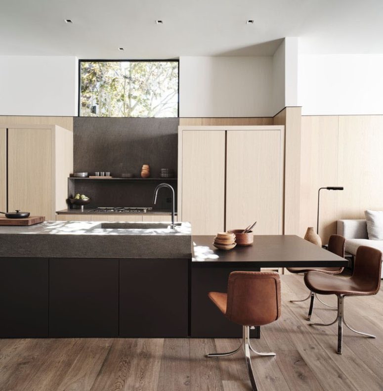 The kitchen is done with sleek light-colored cabinets, a dark kitchen island and brown chairs