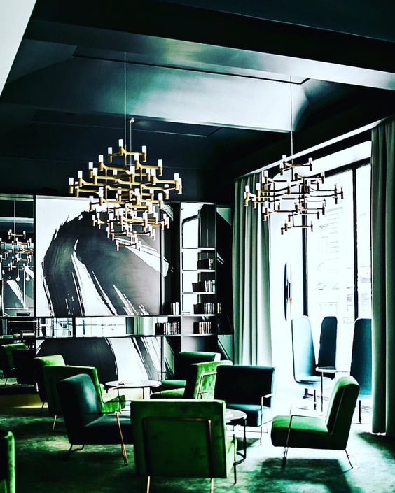 a chic opulent space done in greens and teal, with statement chandeliers and comfy furniture