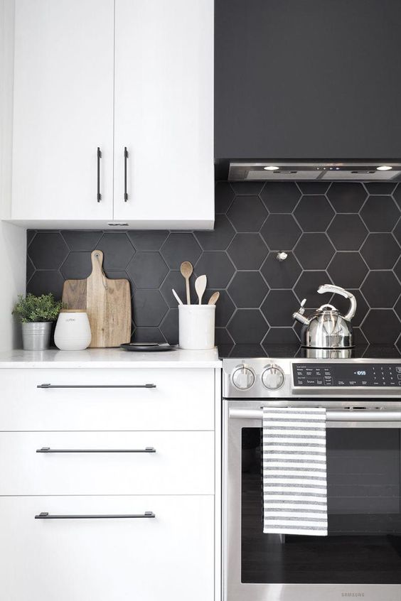 a minimalist white kitchen with a matte black hexagon tile backsplash, which is accented with white grout
