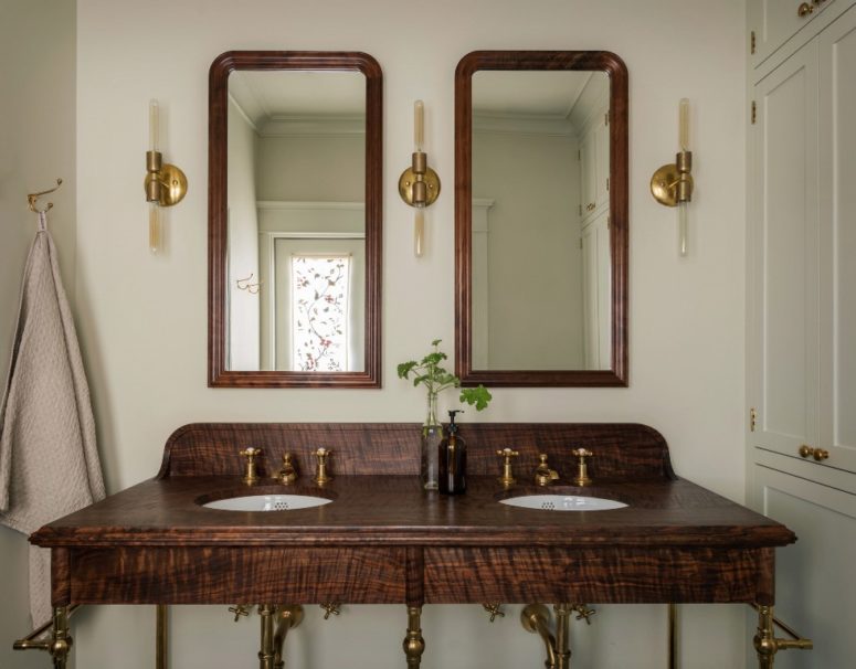 The bathroom features a dark walnut wooden vanity with brass touches and a duo of mirrors