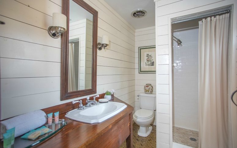 The bathroom is done with white shiplap and tiles, a walk-in shower and a vanity of rich stained wood