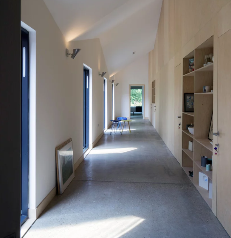 The hallway is long and light-filled, with a whole wall taken by plywood storage furniture