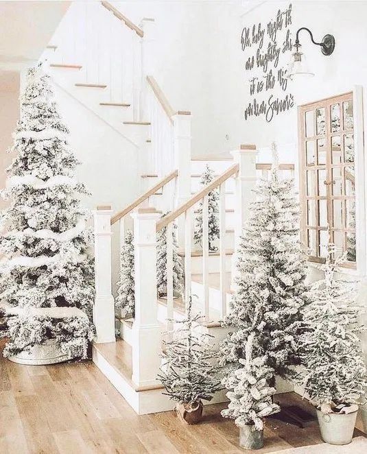 a winter entryway decorated with lots of flocked Christmas trees of various sizes with no decor is a fairy-tale