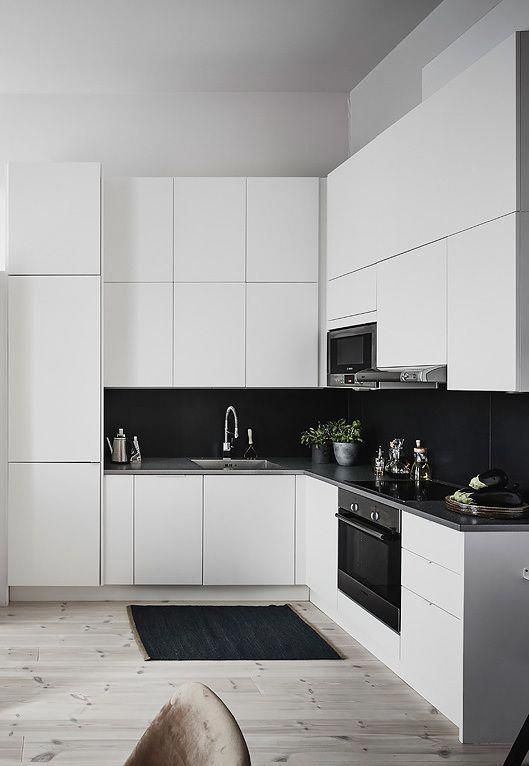 a sleek white kitchen with black large scale tile backsplash that contrasts and stands out a lot