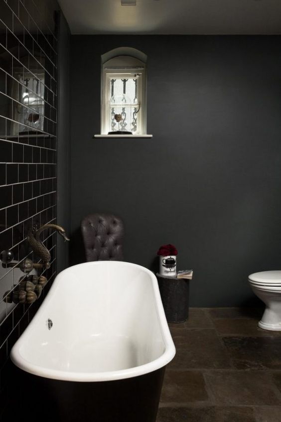 a stylish dark and moody bathroom with a shiny black tile wall and all matte everything plus a black tub