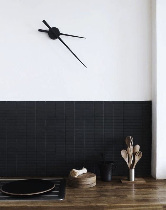 A super contemporary backsplash with matte black long and narrow tiles contrasts the light colored butcher block