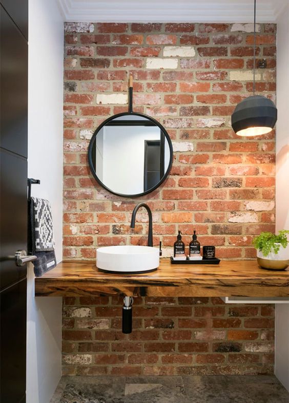 a contemporary bathroom is made cooler and more modern with a red brick wall and a felt pendant lamp