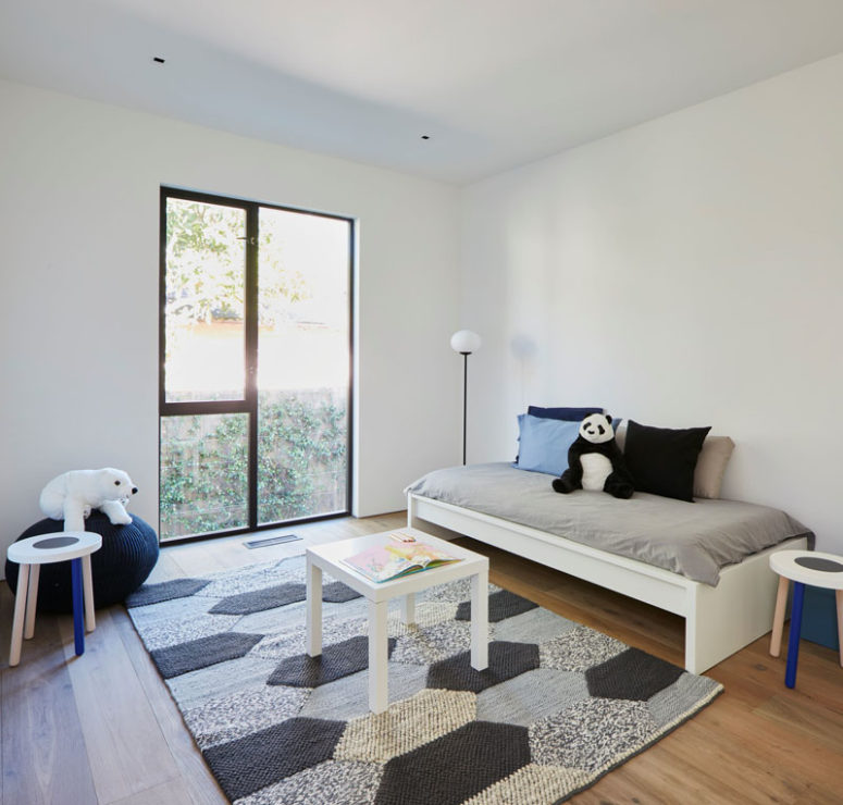 The second kid's room is also rather minimal but with a comfy rug and colorful pillows