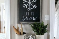 12 a chalkboard sign, a white pompom garland that imitates snowballs and some greenery and cotton in cans