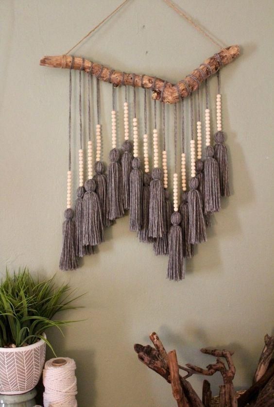 a cool boho wall hanging with large grey tassels and wooden beads and a natural branch is very bold