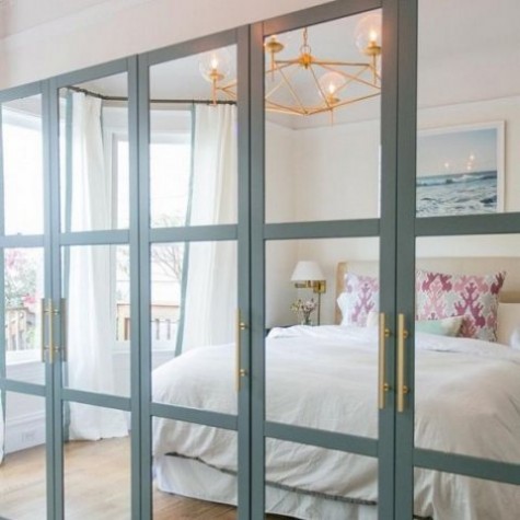 an IKEA Pax wardrobe with fully mirrored front panels with aqua frames and brass handles