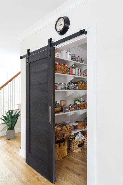 a farmhouse pantry with a dark sliding door, which doesn't take any space and makes a statement with its color