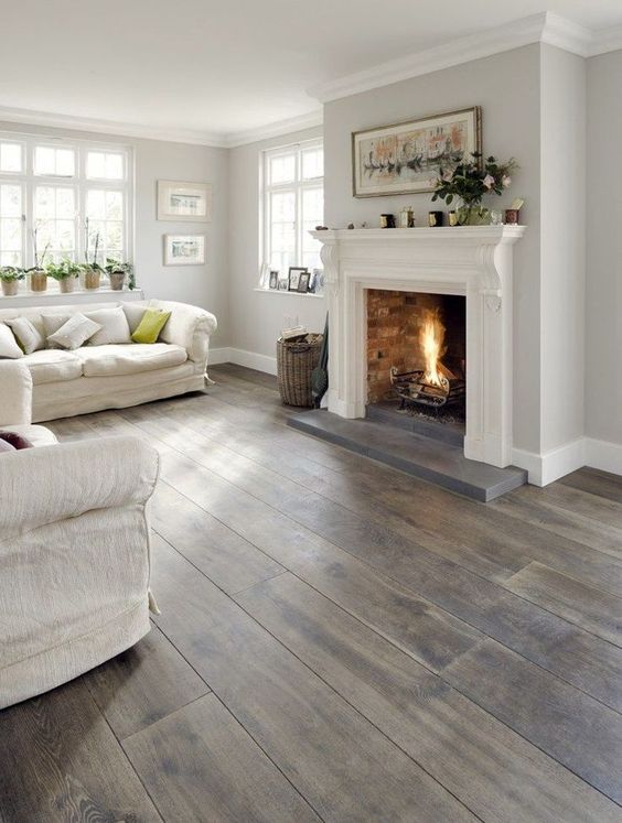 a neutral rustic living room with a grey hardwood tone floor that brings a touch of warm color and coziness