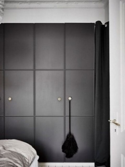 an IKEA Pax wardrobe with black molded doors and metal knobs for a minimalist space